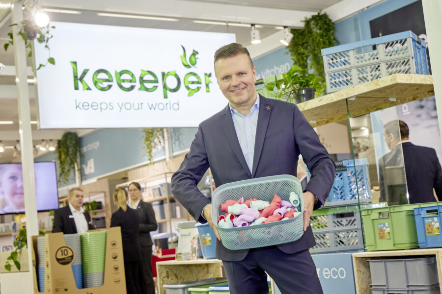 Représentant de keeeper présentant un panier de rangement rempli de jouets lors du salon ambiente 2024, devant le stand de la marque et ses solutions d’organisation durables.