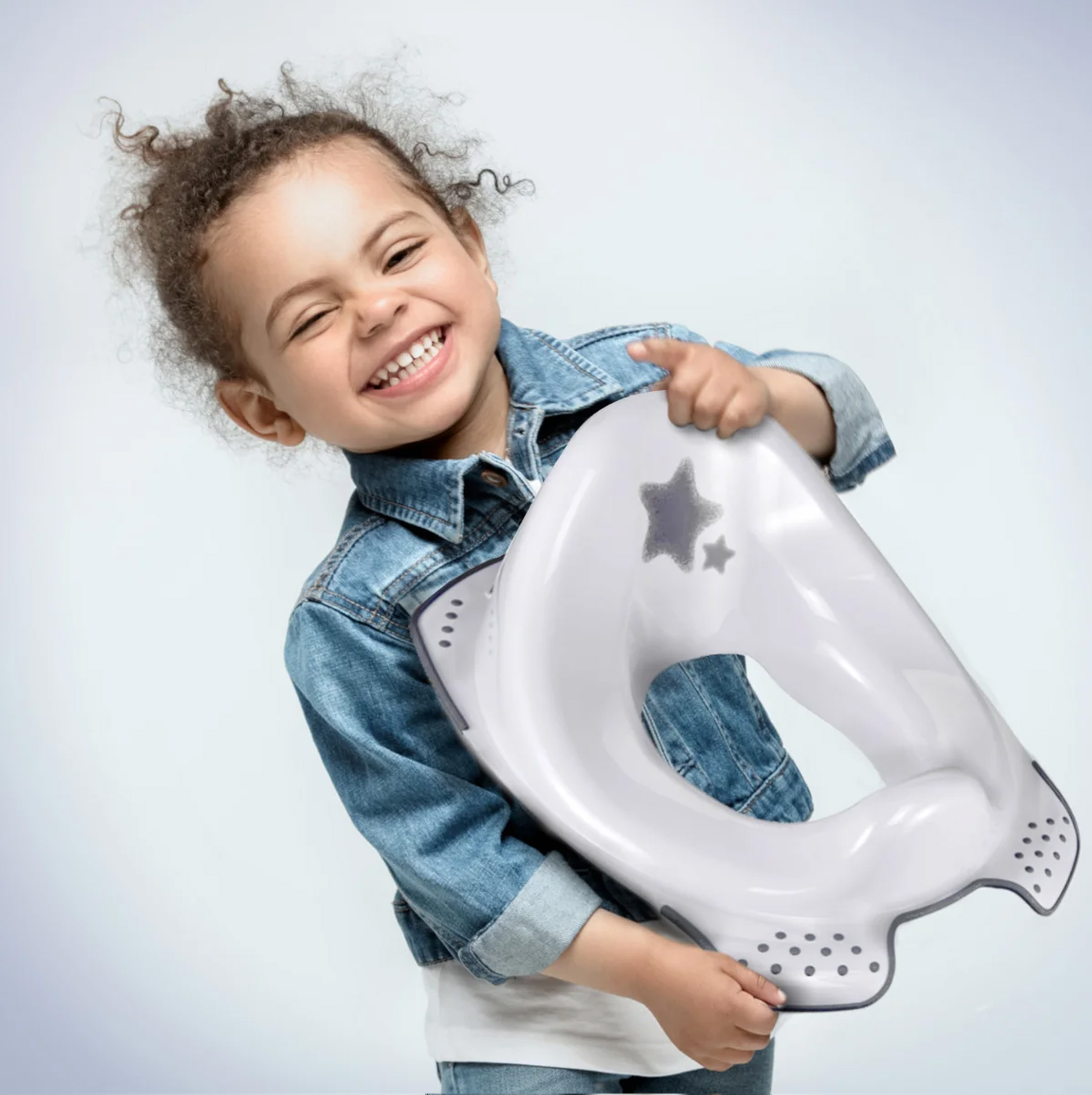 Happy toddler holding a children’s toilet training seat.